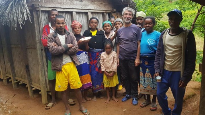 Alfonso et une famille de 11 personnes posent devant la case en bois pour la photo finale